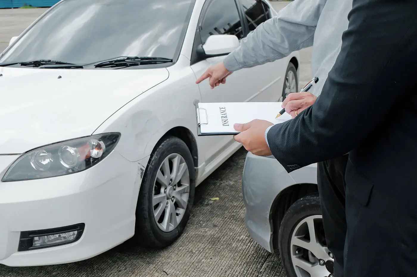 Ajustador inspeccionando un vehículo dañado junto a su dueño