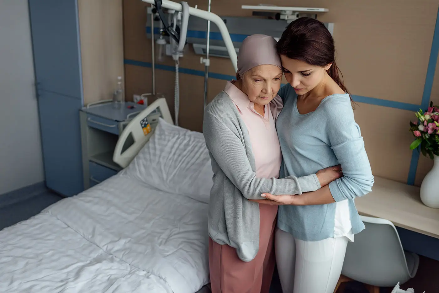 Una mujer abraza a su madre enferma en una habitación de hospital