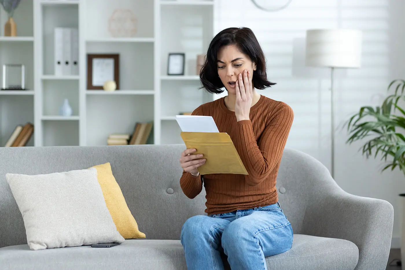 Mujer sorprendida y preocupada leyendo una carta en su sofá