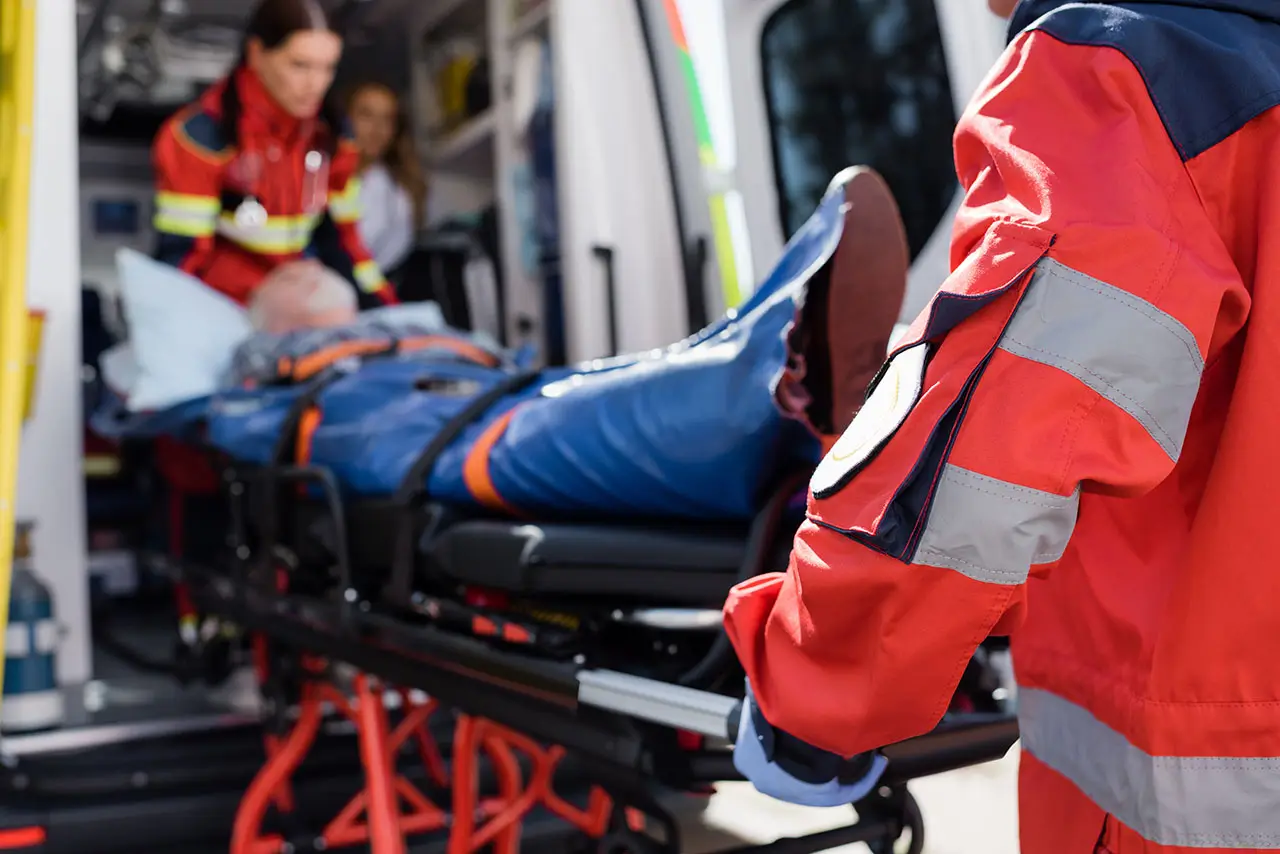 Paramédicos suben una camilla con un paciente a la ambulancia