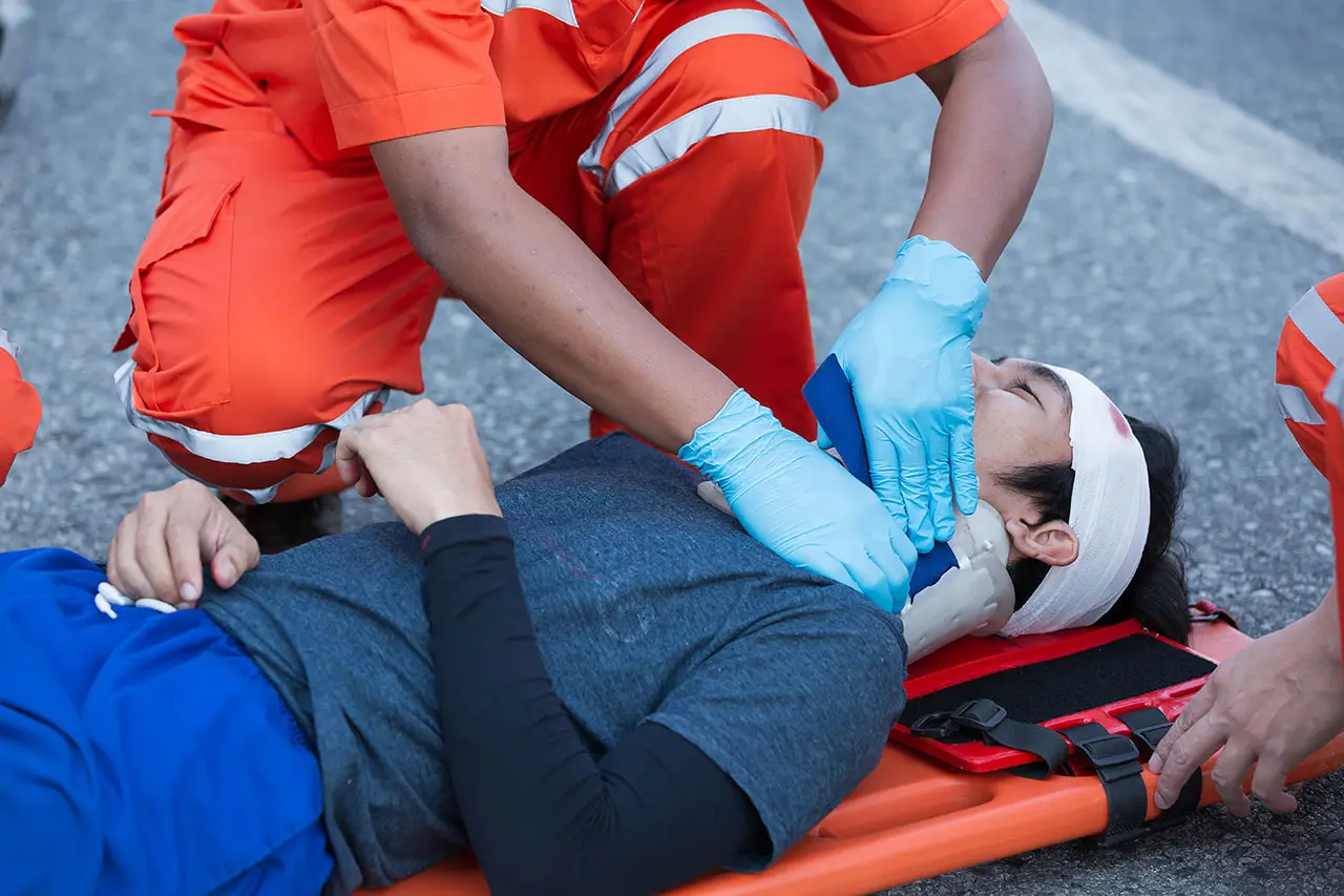 Paramédicos atienden a un herido en una camilla en plena vía