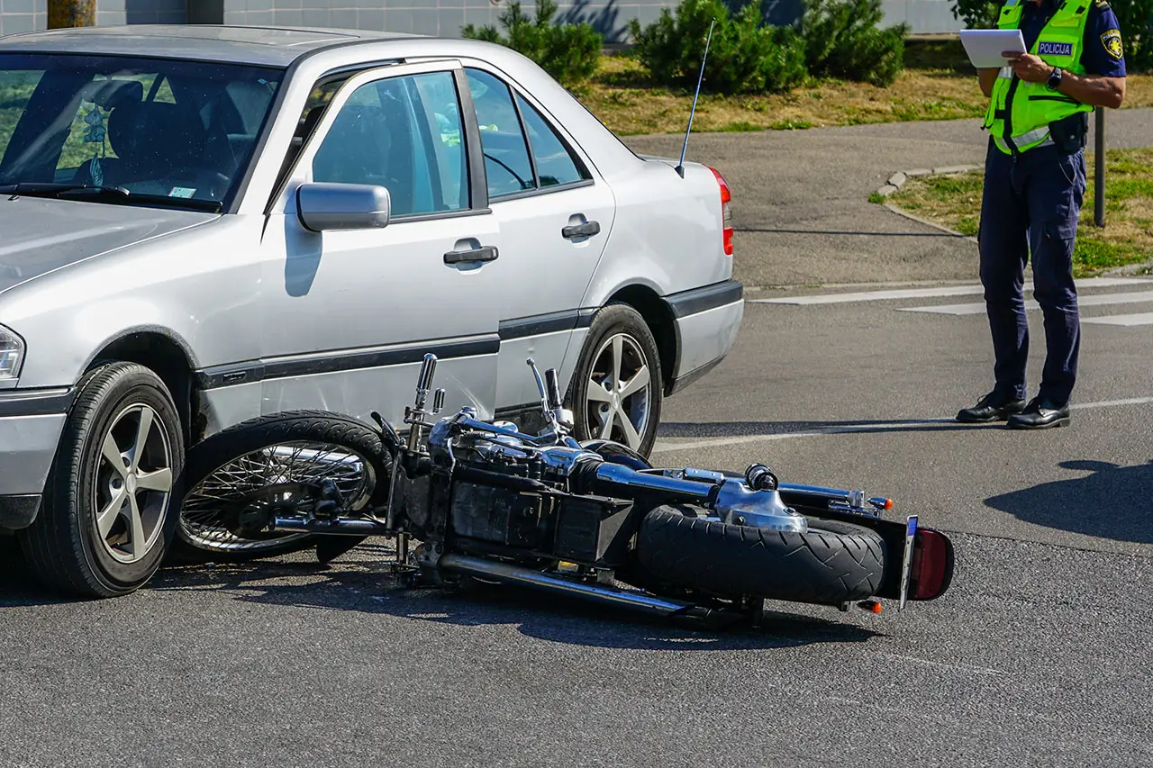 Moto caída junto a un carro después de una colisión en la ciudad