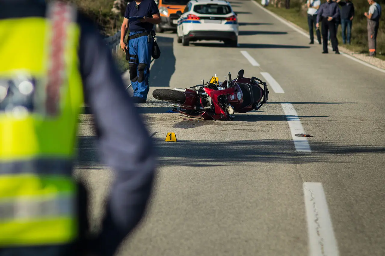 Moto accidentada en la carretera, con la policía en el lugar del accidente